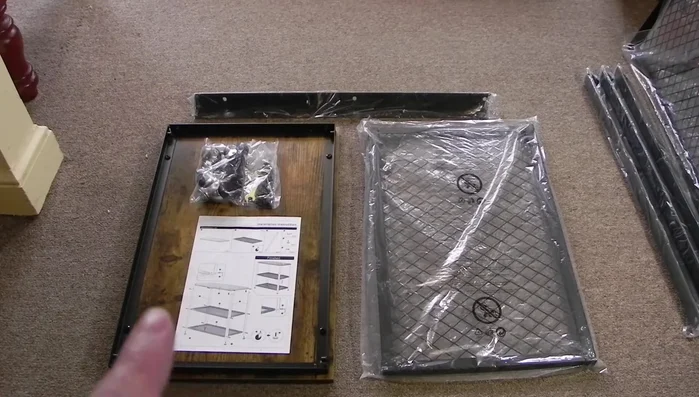Unboxing and identifying components: instructions, hardware (bolts, wrench, hex key), top, shelves, and side braces.