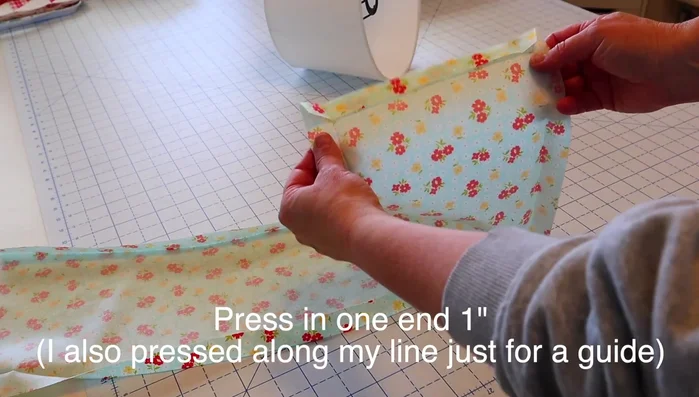 Press in one short end of the fabric by about an inch. Press along the drawn line to create a guide.