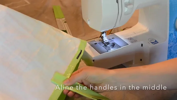 Attach the handles to the bag by sewing them onto the middle of the top seam.