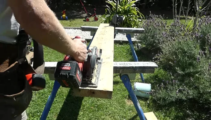 Install two timber joists to the existing concrete walkway and one to the retaining edge for the lower deck.