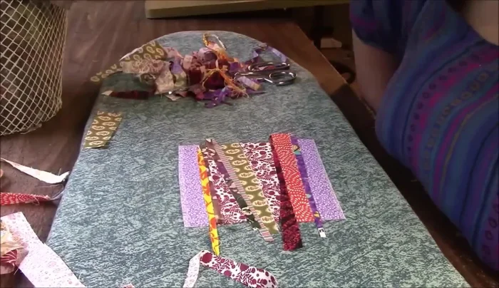 Press the arranged fabric pieces to adhere them to the backing fabric.