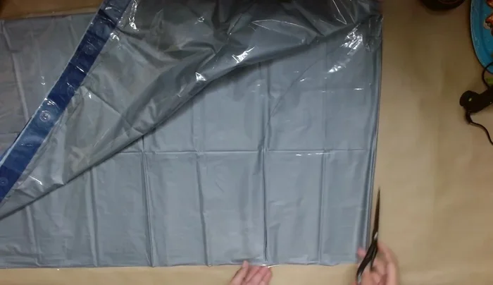 Create the playhouse structure: Fold the double-layered shower curtain in half. Draw and cut a doorway opening. Secure the edges of the doorway with painter's tape to keep it stable.