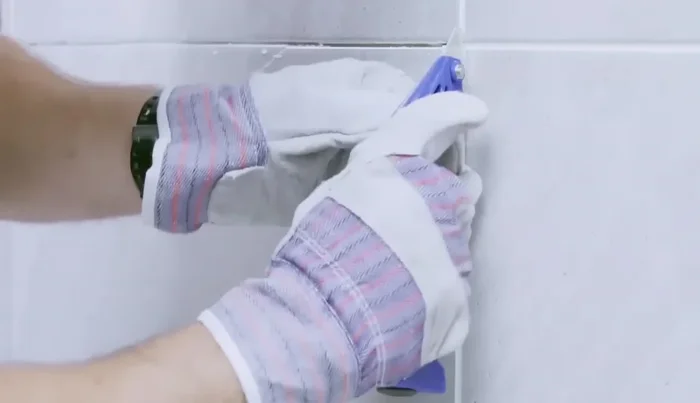 Remove the tape and grout around the damaged tile using a grout removing tool (50.64).