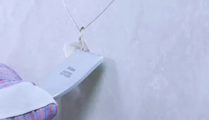 Clean the wall surface of any remaining adhesive using a scraper or hammer and chisel (78.68).