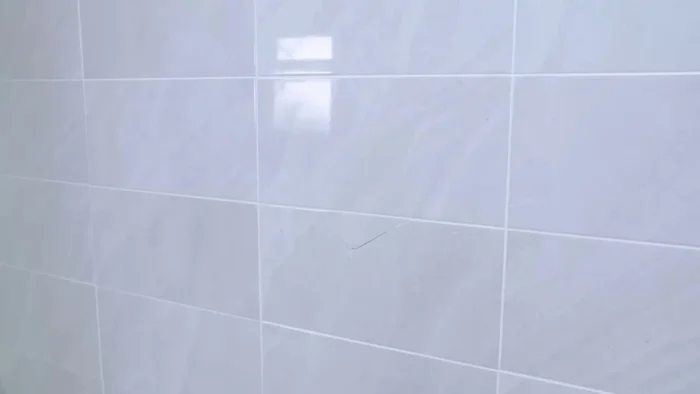 Remove the tape and grout around the damaged tile using a grout removing tool (50.64).