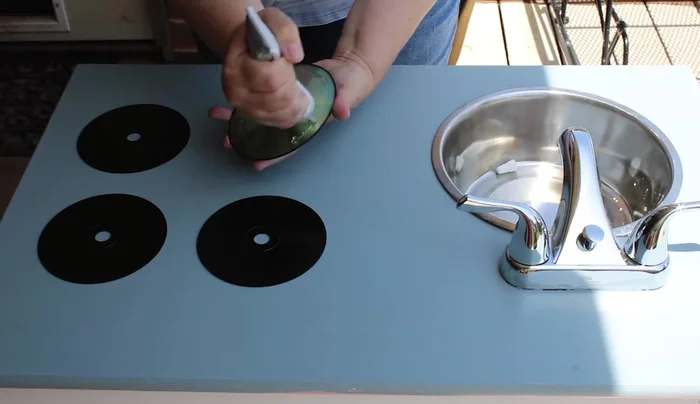 Spray paint CDs and adhere them to the cabinet as stove burners using E6000.