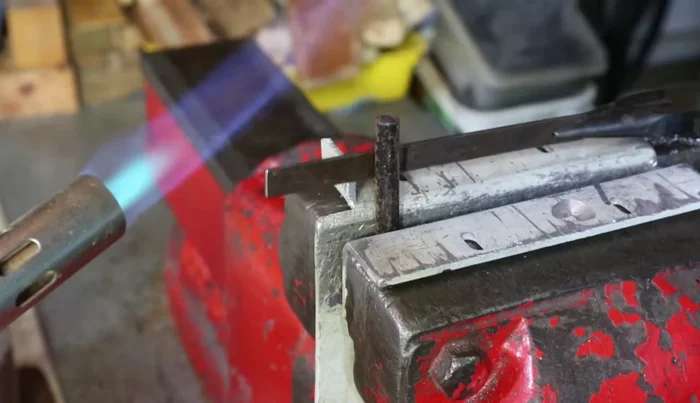 Use the vice to press the edges of the U-shaped spring inward to create a tighter fit around the rod.