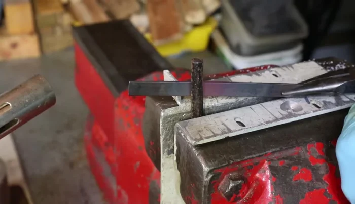 Use the vice to press the edges of the U-shaped spring inward to create a tighter fit around the rod.