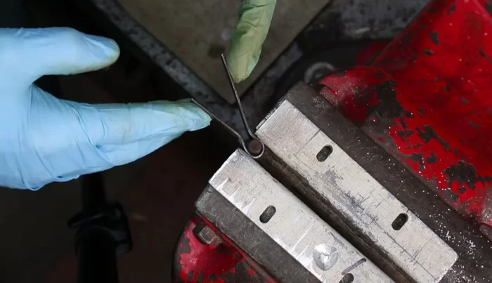 Bend the ends of the spring to match the desired shape using the drawing as a guide and the vice.