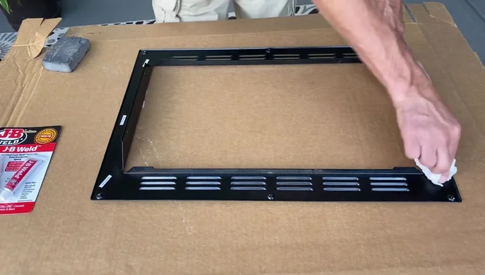 Clean the metal frame surface with detergent, then roughen it up using a sanding block or sandpaper to improve JB Weld adhesion.