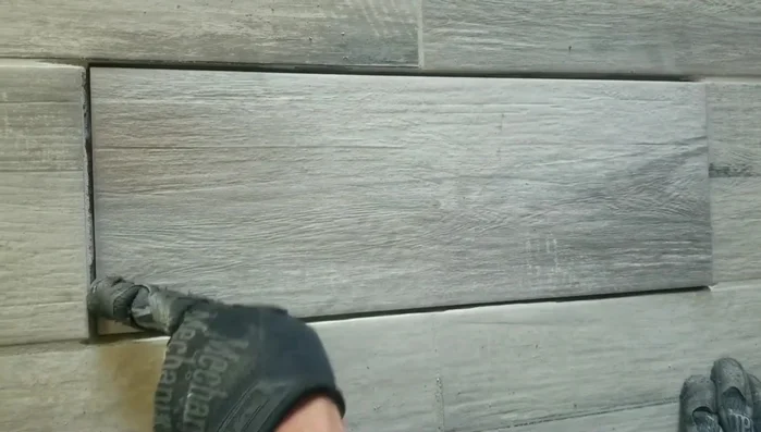 Dry-fit the new tile to check for fit and adjustments needed. Check for lippage and make adjustments to the surrounding mortar to ensure a flush fit. Matching the grain direction of the new tile is also important.