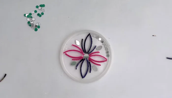 Arrange and adhere mosaic pieces: Carefully arrange your bangle pieces and mirrors (if using) onto the putty, ensuring they are firmly attached. If the thickness varies between the bangles and mirrors, double the thinner pieces to even out the surface.