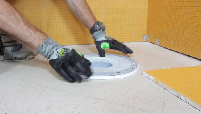 Apply thinset to the top and bottom of the halved foam insert and place it between the floor and the drain for support.