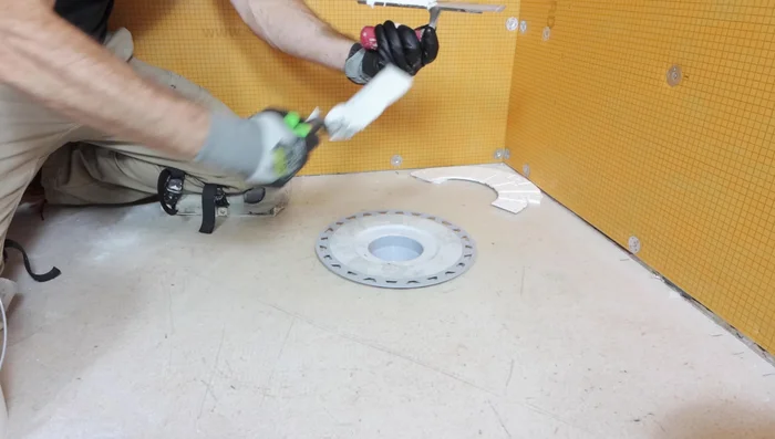 Apply thinset to the top and bottom of the halved foam insert and place it between the floor and the drain for support.