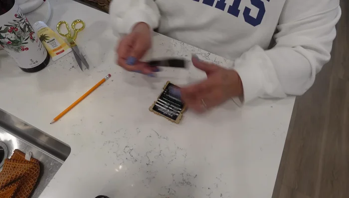 Apply hot glue to the back of your photos and carefully place them within the miniature frames, ensuring they are centered and secure.