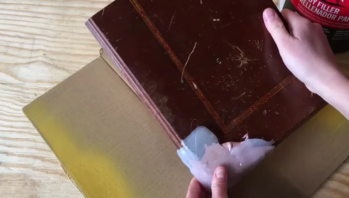 Press the hot glue mold onto the Bondo, ensuring good contact with the existing wood. Hold for a few minutes until the Bondo starts to harden.