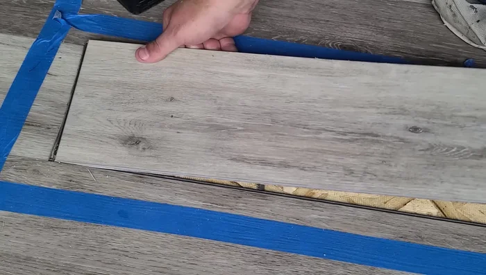 Tap the plank into place using a tapping block and rubber mallet, ensuring even pressure and avoiding damage.