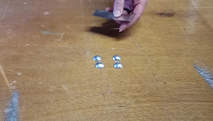 Assemble the beads by wrapping a thin strip of aluminum tape around two domed aluminum pieces. Press the tape firmly and smooth the edges with an embossing tool.