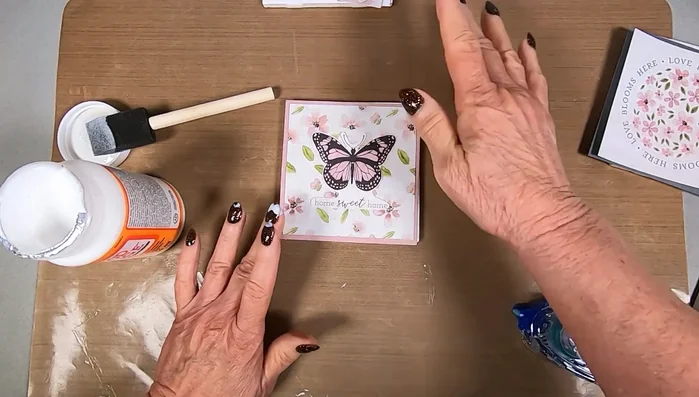 Place the prepared scrapbooking paper face down onto the Mod Podge-coated tile. Smooth out any wrinkles or air bubbles, working from the center outwards.