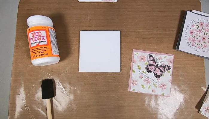 Prepare the tiles: Apply an even coat of Mod Podge to the back of each ceramic tile, extending to the edges.