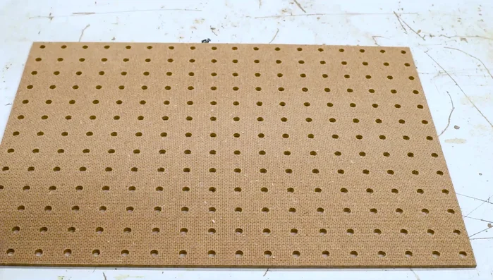 Cut pegboard to fit, attach 1x2 scrap pieces to underside for elevation. Attach with wood glue and brad nails.