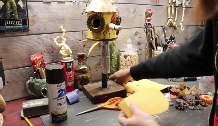 Create and attach the mouth: Cut a mouth shape from a 5-gallon bucket. Attach teeth and gears.