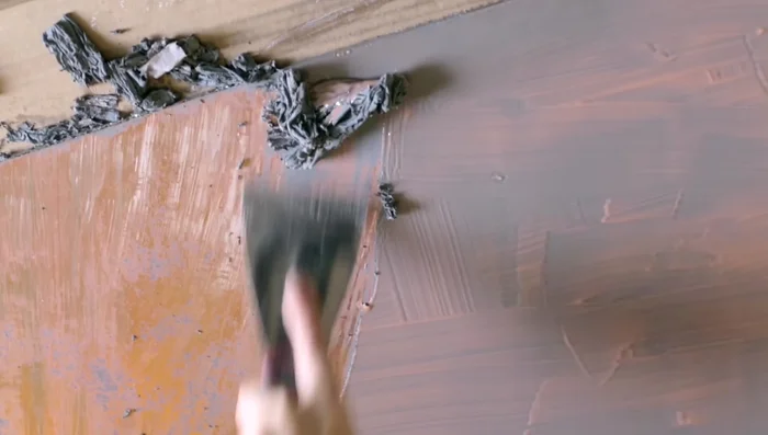 Use a putty knife to carefully remove the gray backing. Be cautious not to scrape the gold layer underneath.