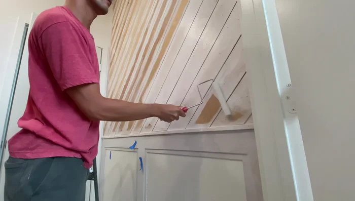 Fill nail holes with spackle and paint the upper wall black, contrasting with the white lower third.