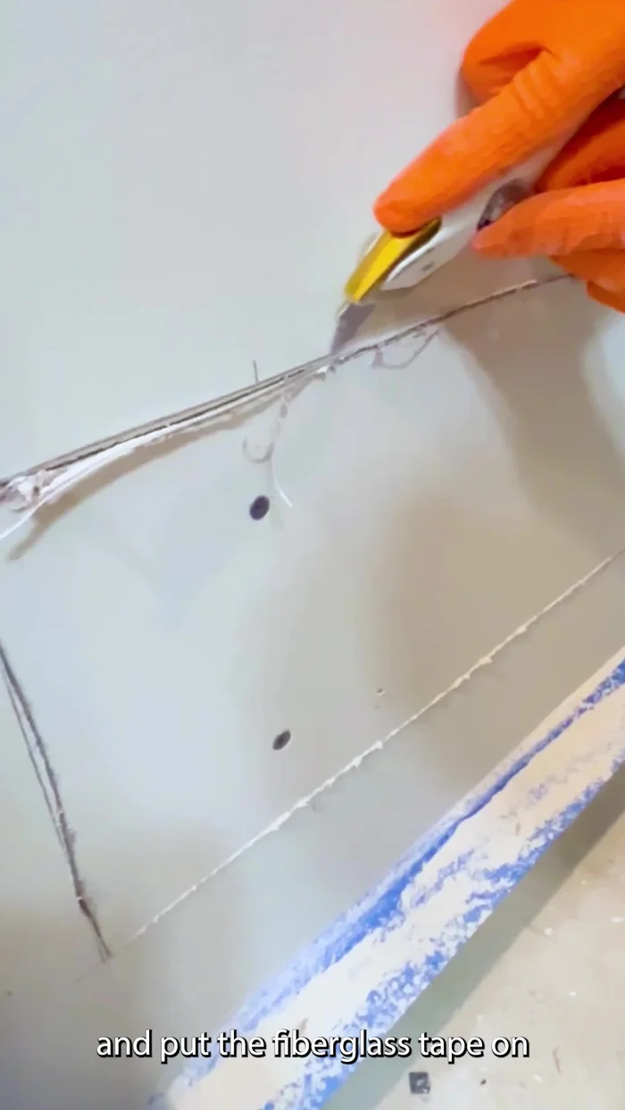 Prepare the edges of the damaged drywall by using a razor knife to cut the face paper at a 45-degree angle for a clean, smooth surface.