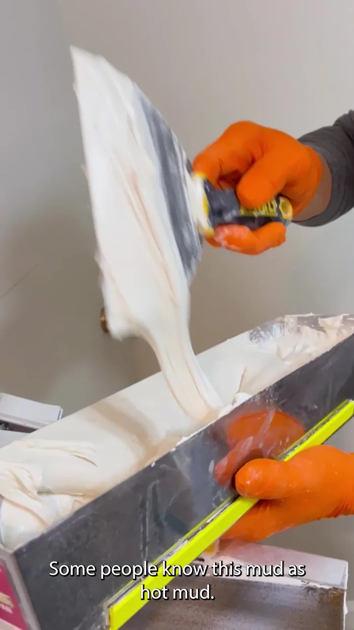Apply the first coat of hot mud, ensuring even coverage on both sides of the seam. Use a 10-inch knife and a 6-inch knife to get into tight spaces and feather the edges. This widens the mudded area.