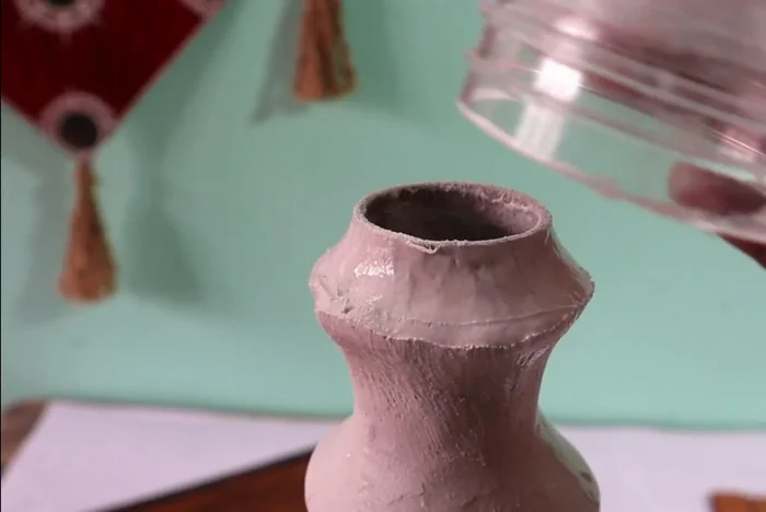 Attach the top piece: Attach the top plastic bottle piece using wall putty and a cloth to ensure a secure bond.