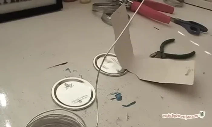 Optionally, curl the wire by coiling it around a pen. Twist the two ends together to secure, making the loop narrow enough to fit through the jar ring.