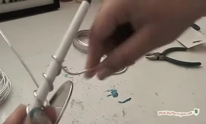 Optionally, curl the wire by coiling it around a pen. Twist the two ends together to secure, making the loop narrow enough to fit through the jar ring.