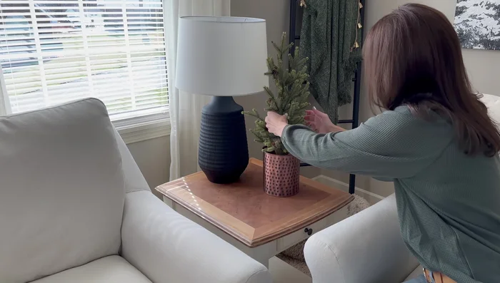 Style a corner end table with a grouping of three items: a pine tree in a hammered copper crock, a black deer, and a candle.