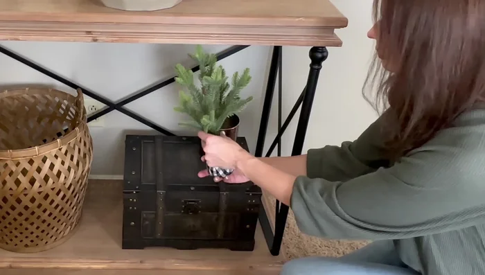 Decorate the bottom of the console table with a small pine tree in a copper canister, a small tray with bells, and a cozy blanket.