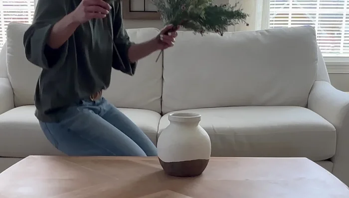 Style the coffee table with a thrifted vase, florals, a Christmas coffee table book, and a green glass candle.