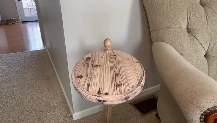 Style an accent table with a marble tray, a wreath, a black light-up ceramic house, and a cloche.