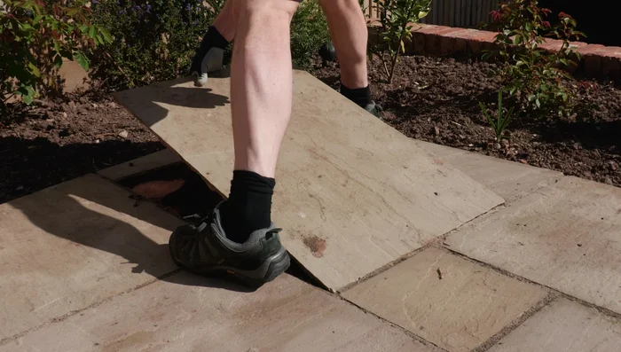 For larger repairs (like a sunken corner), completely excavate the area, remove loose material, and tamp down any remaining bedding mortar.