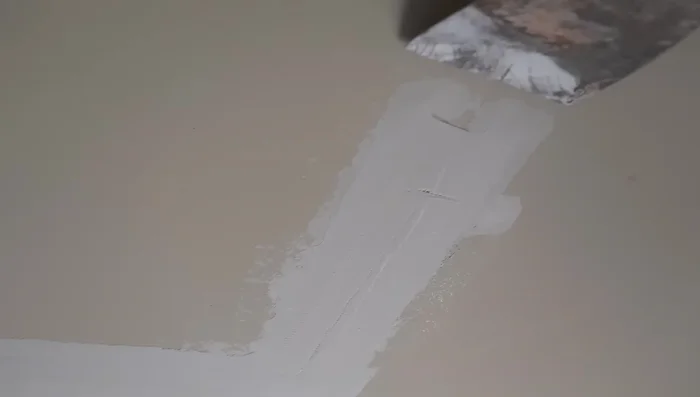 Scrape and sand the first coat: Remove any high spots with a scraper and lightly sand the edges if necessary.