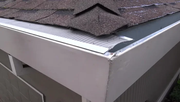 For outside corners, let the mesh run long to the end of the gutter. Bend the back aluminum extrusion into the gutter; no cutting is necessary. Mark the adjoining piece at the same angle as the roof ridge and use tin snips to cut.