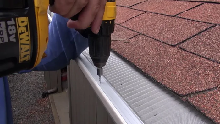 Fasten three self-tapping screws for each 4' section using the line guide on the aluminum extrusion as a reference. The screw's drill bit will go through the aluminum and gutter.