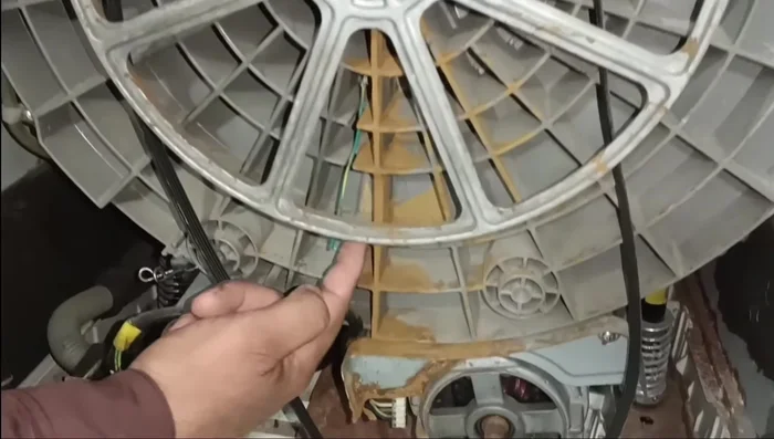 Open the back cover of the washing machine. The pulley is jammed due to rust.