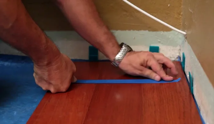 Use blue painter's tape to hold the floor in place while the glue cures (Do not use regular masking tape).