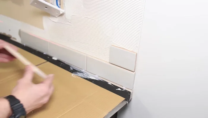 Cut tiles around outlets, stopping at the drywall.