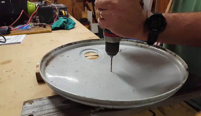 Drill a hole in the center of the drum lid, then sand it down.