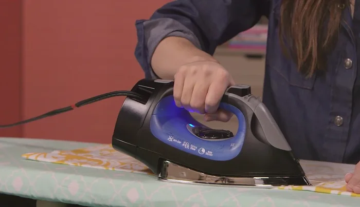 Press hems: Press all hems and corners flat. Add fabric adhesive to the underside of mitered corners and press again.