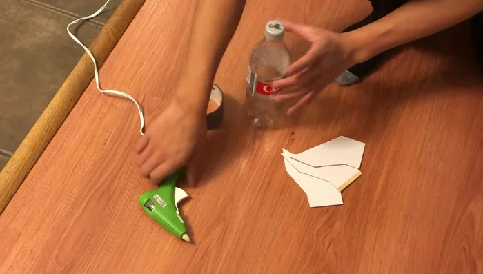 Attach the fins evenly spaced around the bottle using hot glue and duct tape to ensure balance.