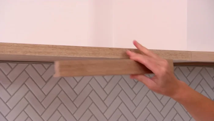 Replace cabinet handles with new ones to match the overall kitchen aesthetic (timber handles in this case).