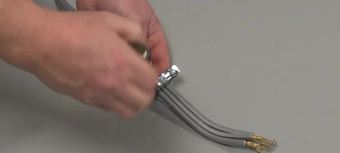 Insert the tabs on the two halves of the strain relief into the power cord hole on the dryer's rear panel and insert the screws to hold the relief together loosely.