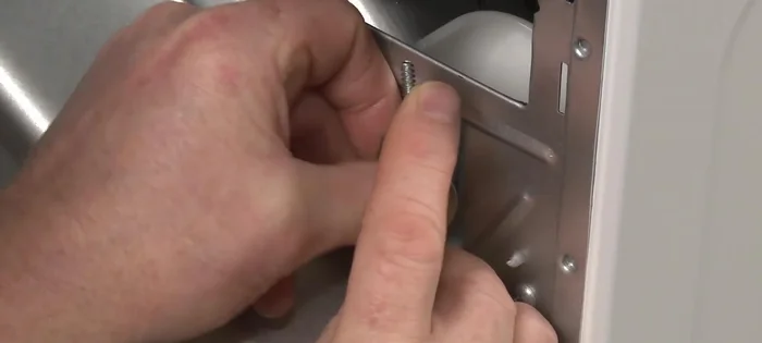 Insert the tabs on the two halves of the strain relief into the power cord hole on the dryer's rear panel and insert the screws to hold the relief together loosely.